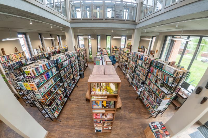 pomieszczenie biblioteki z dużymi oknami oraz wieloma regałami z książkami
