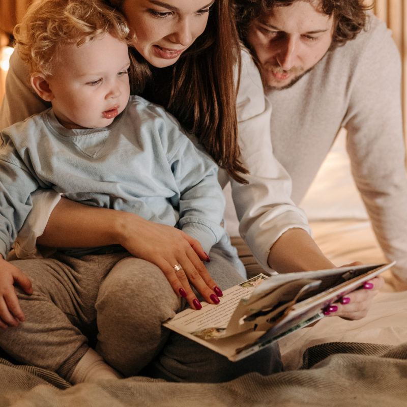 kobieta, mężczyzna i mały chłopiec wspólnie oglądają i czytają książkę