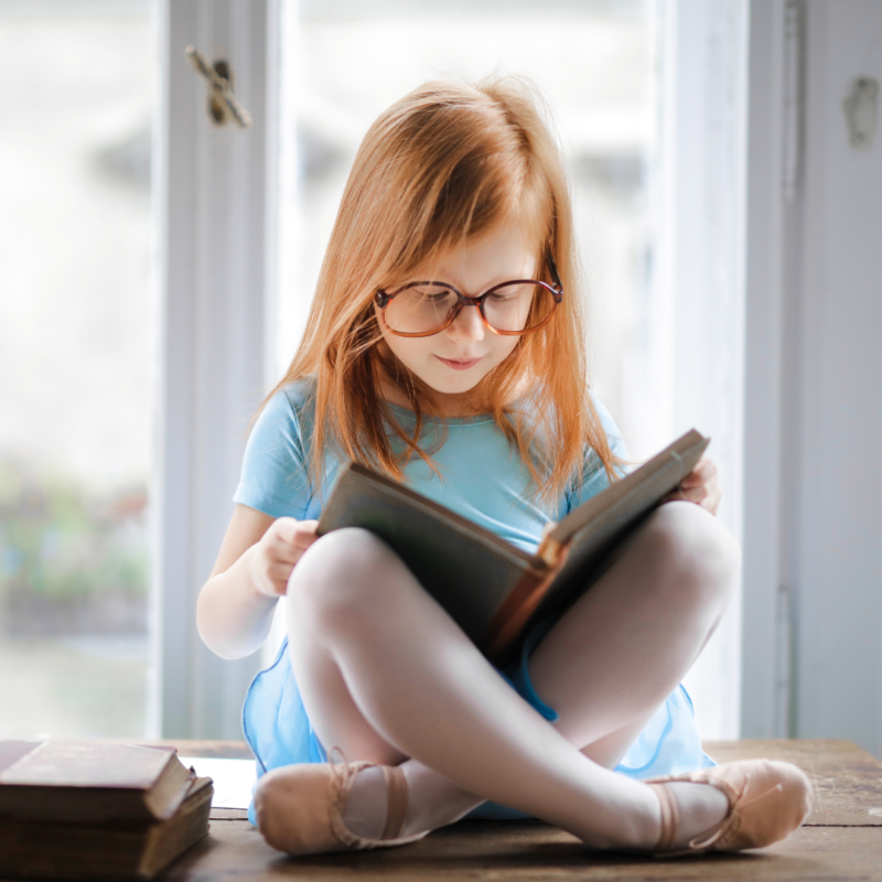 dziewczynka w okularach czytająca książkę