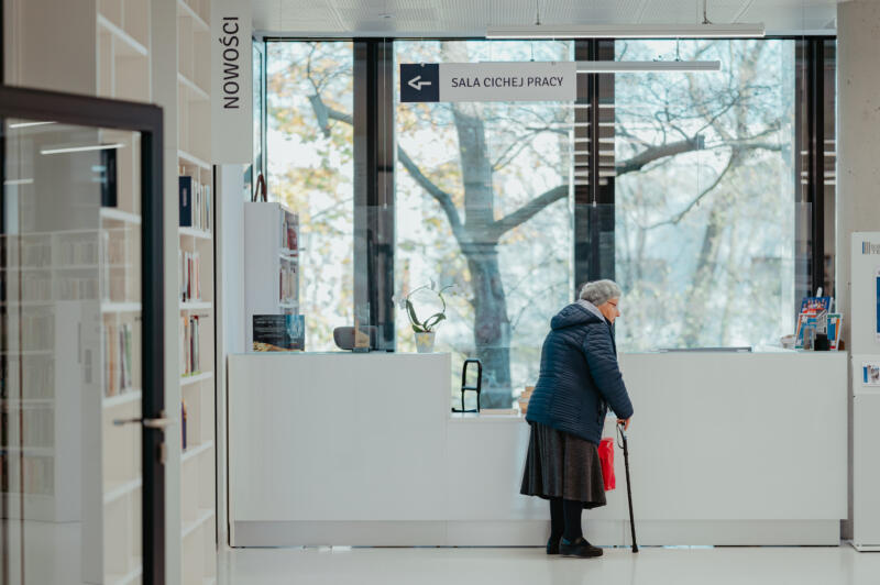starsza kobieta stojąca w korytarzu biblioteki