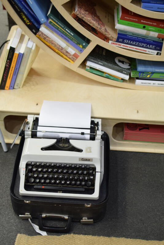 maszyna do pisania obok regału z książkami