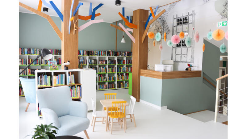 widok na kolorowe pomieszczenie z regałami z książkami i miejscem do czytania